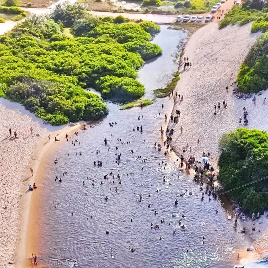 Onde ficar em Salinas: vista panorâmica da Lagoa da Coca-Cola Vista aérea da famosa Lagoa da Coca-Cola em Salinópolis, cercada por dunas de areia branca e vegetação nativa, destacando as águas escuras terapêuticas como opção de lazer para quem busca onde ficar em Salinas, Pará