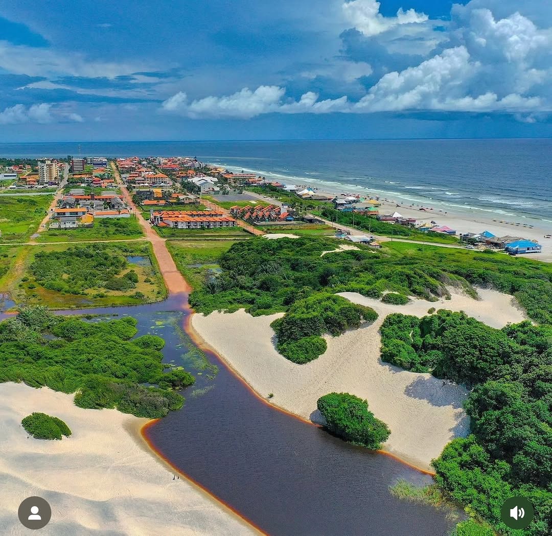 Guia de Visitação Lago da Coca-Cola em Salinópolis - Pará Lago da Coca-Cola em Salinas cercado por dunas de areia branca, destacando a água de tom escuro avermelhado característica da região.